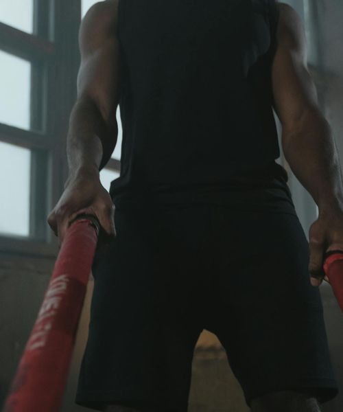 Man performing a controlled strength exercise in a dark gym.